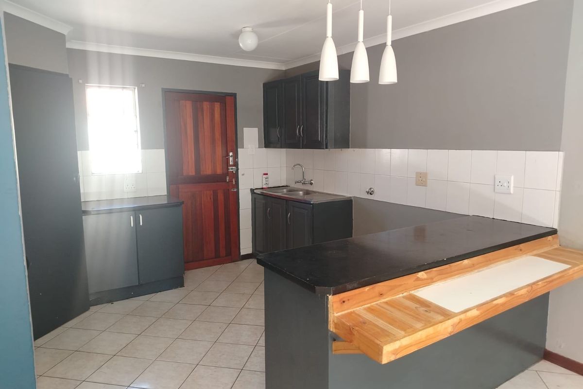 A functional kitchen featuring dark cabinetry, a breakfast bar, tiled flooring, and a tiled backsplash, offering a clean and practical layout.