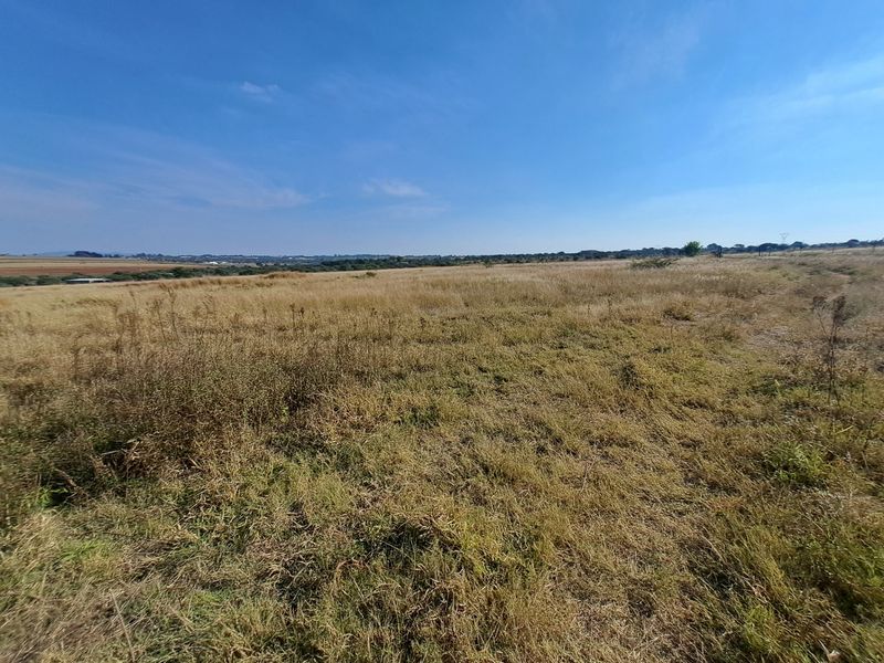 Expansive open landscape view across the farm property, showcasing natural terrain and open fields under a clear sky.