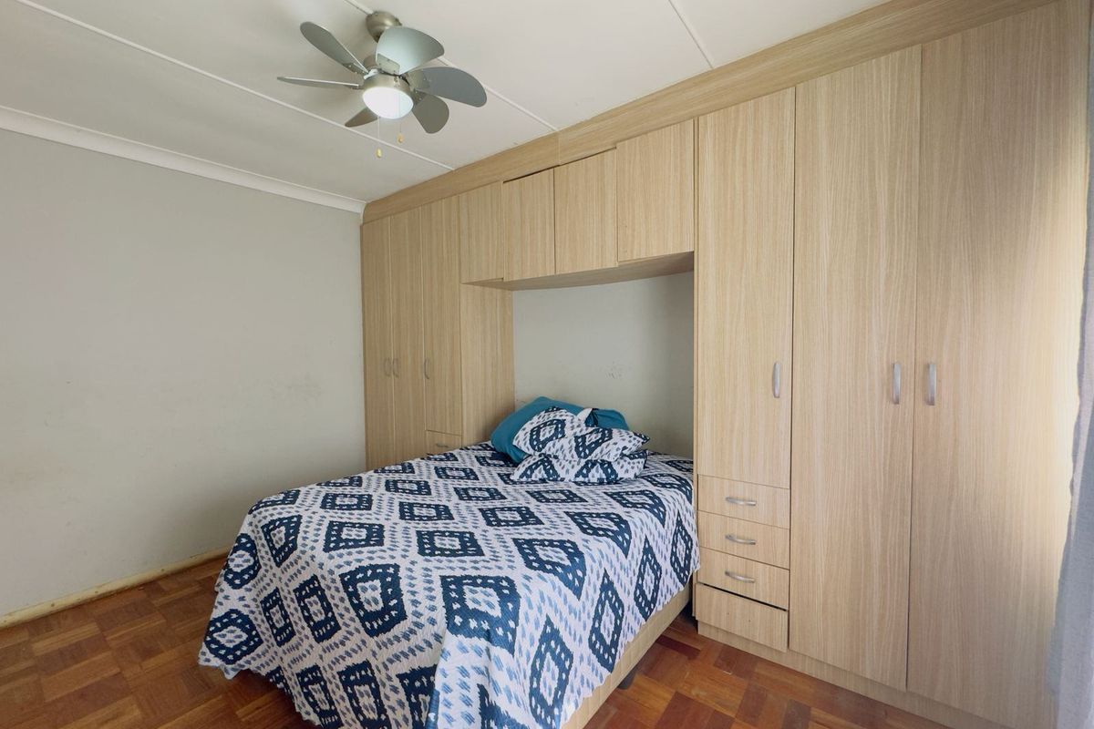 A bedroom featuring extensive light wood built-in cabinetry, a ceiling fan, and traditional parquet flooring.