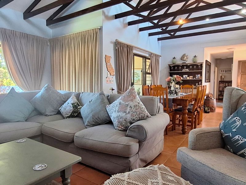 Spacious open-plan living and dining area featuring high vaulted ceilings with exposed timber trusses and tiled flooring throughout.