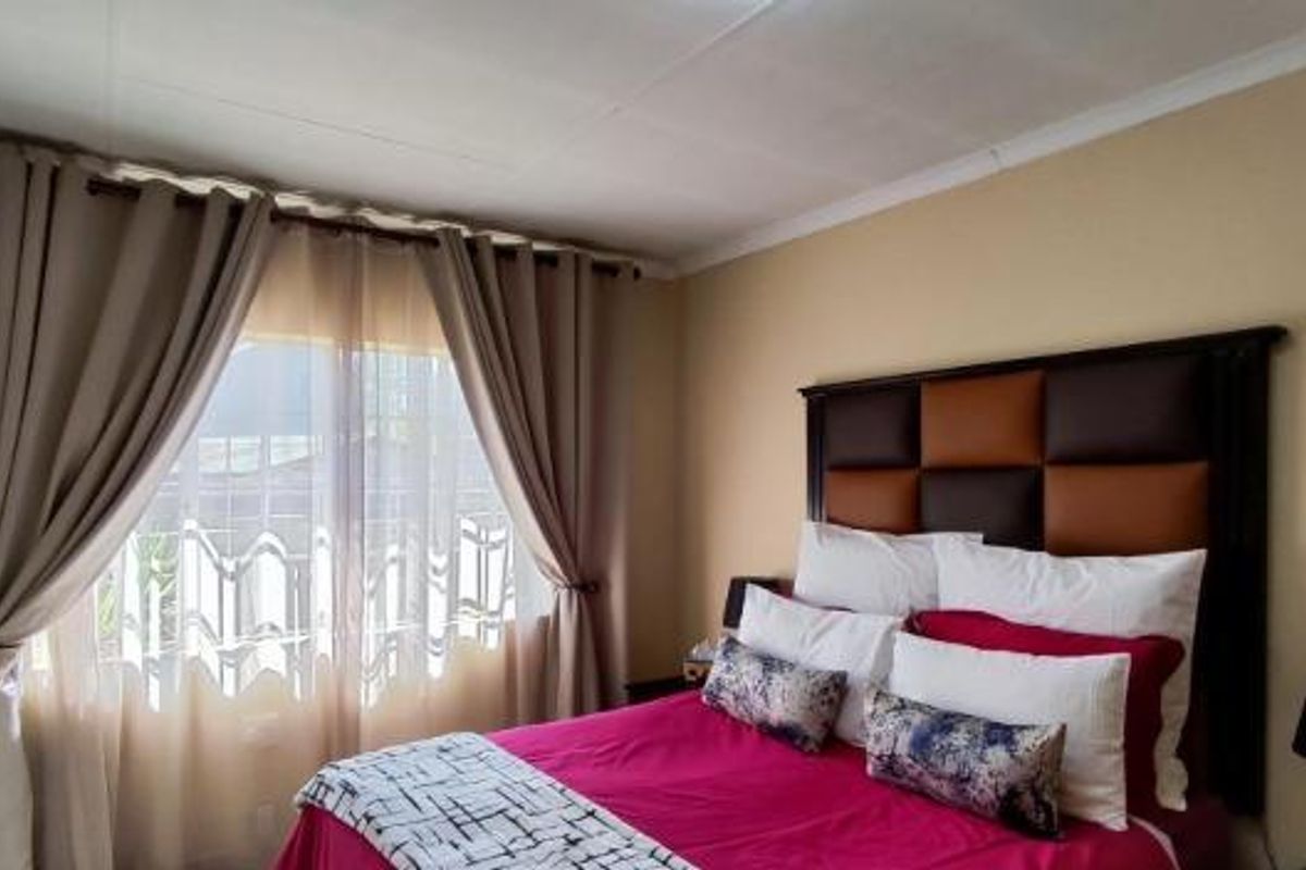 A well-lit bedroom featuring neutral wall tones and a large window with installed curtain rods.