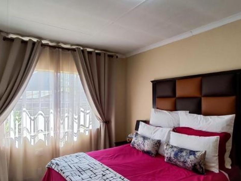 A well-lit bedroom featuring neutral wall tones and a large window with installed curtain rods.
