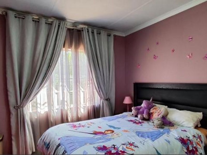 A bedroom featuring mauve-painted walls, coving, and window treatments, providing a functional space with neutral architectural finishes.