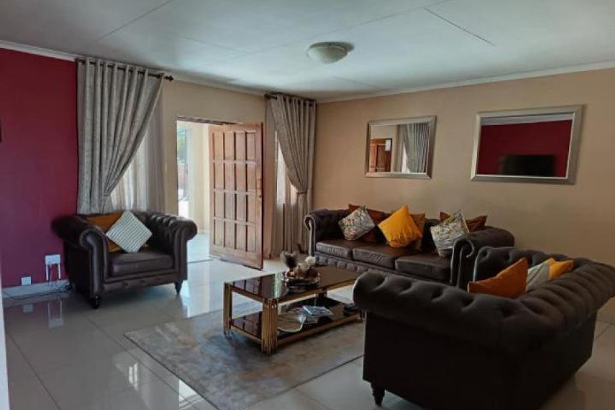 A spacious living room featuring tiled flooring, a feature wall, and direct access to an outdoor area through a timber door.