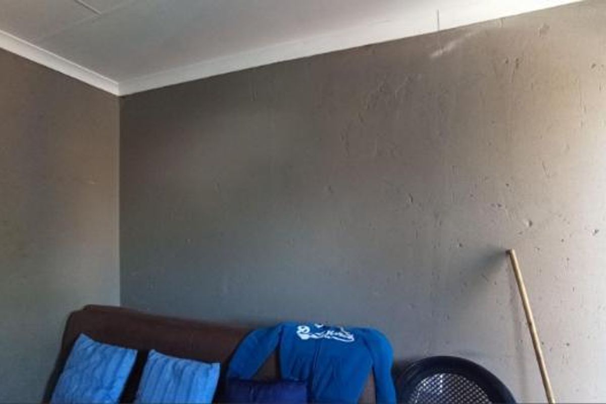 A living room area featuring dark painted walls with visible plaster texture and coving detail.