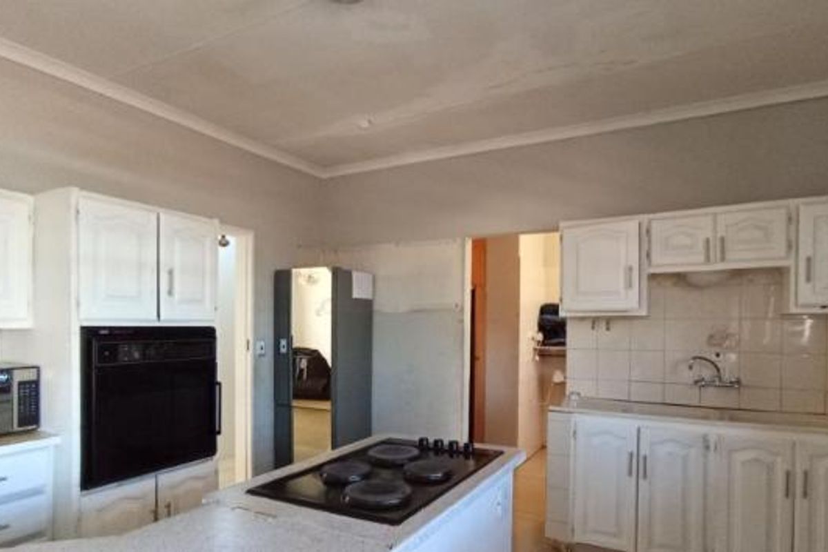 A dated kitchen featuring built-in cabinetry, an integrated oven, and a central hob, offering significant potential for modernization and renovation.
