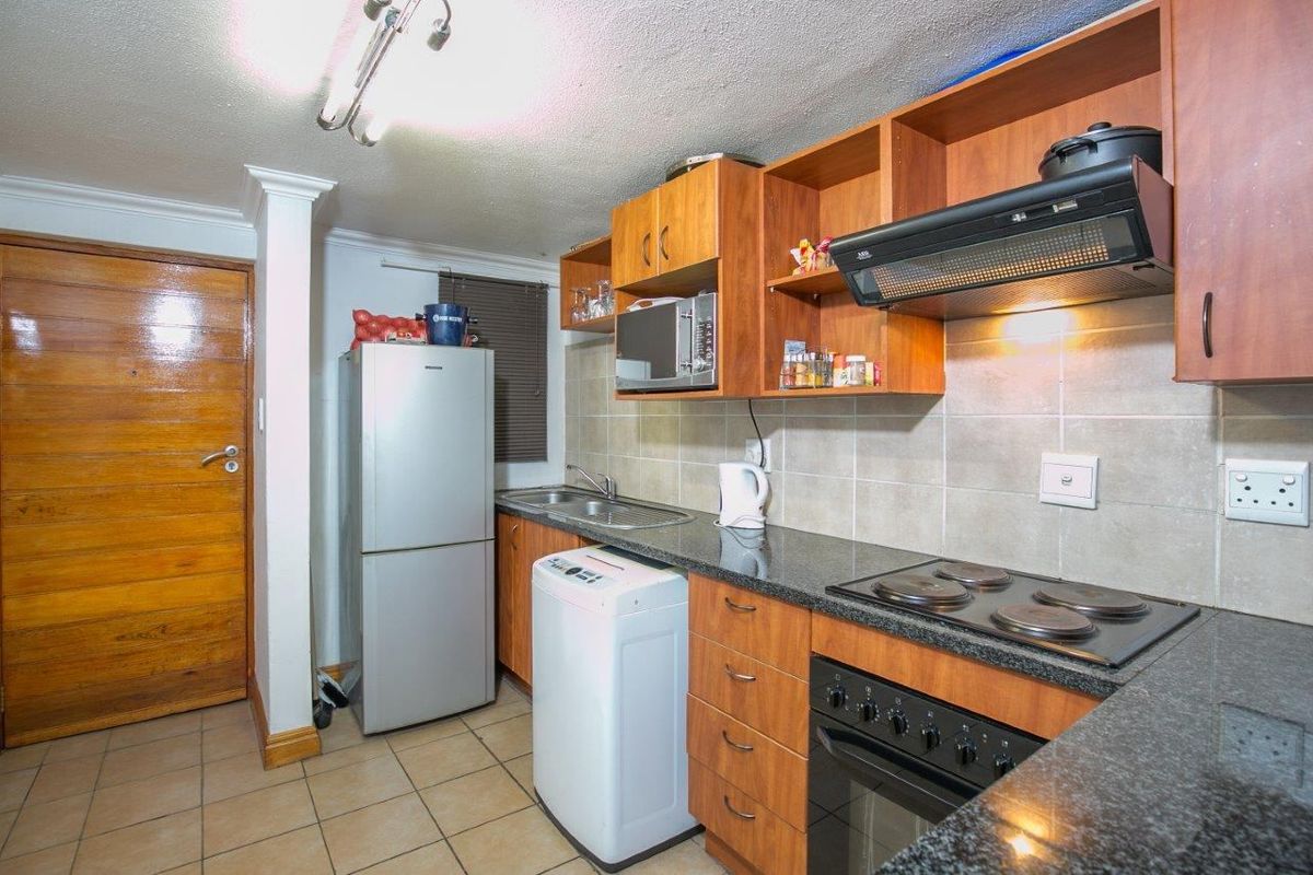 A functional kitchen featuring wood-finish cabinetry, granite countertops, a built-in oven and hob, and tiled backsplash, offering a practical layout for daily use.