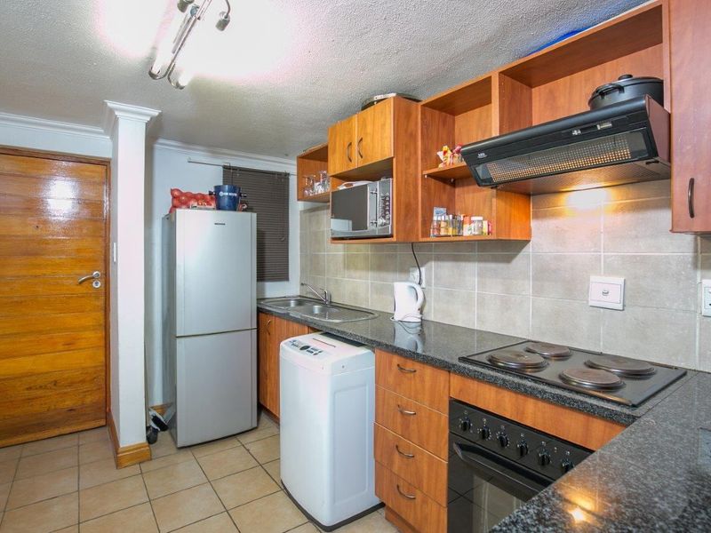 A functional kitchen featuring wood-finish cabinetry, granite countertops, a built-in oven and hob, and tiled backsplash, offering a practical layout for daily use.