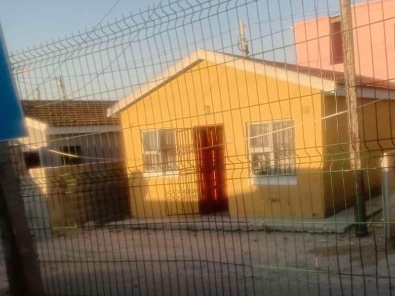 Front view of a single-story residential house featuring a yellow facade, security gate, and protective wire mesh fencing.