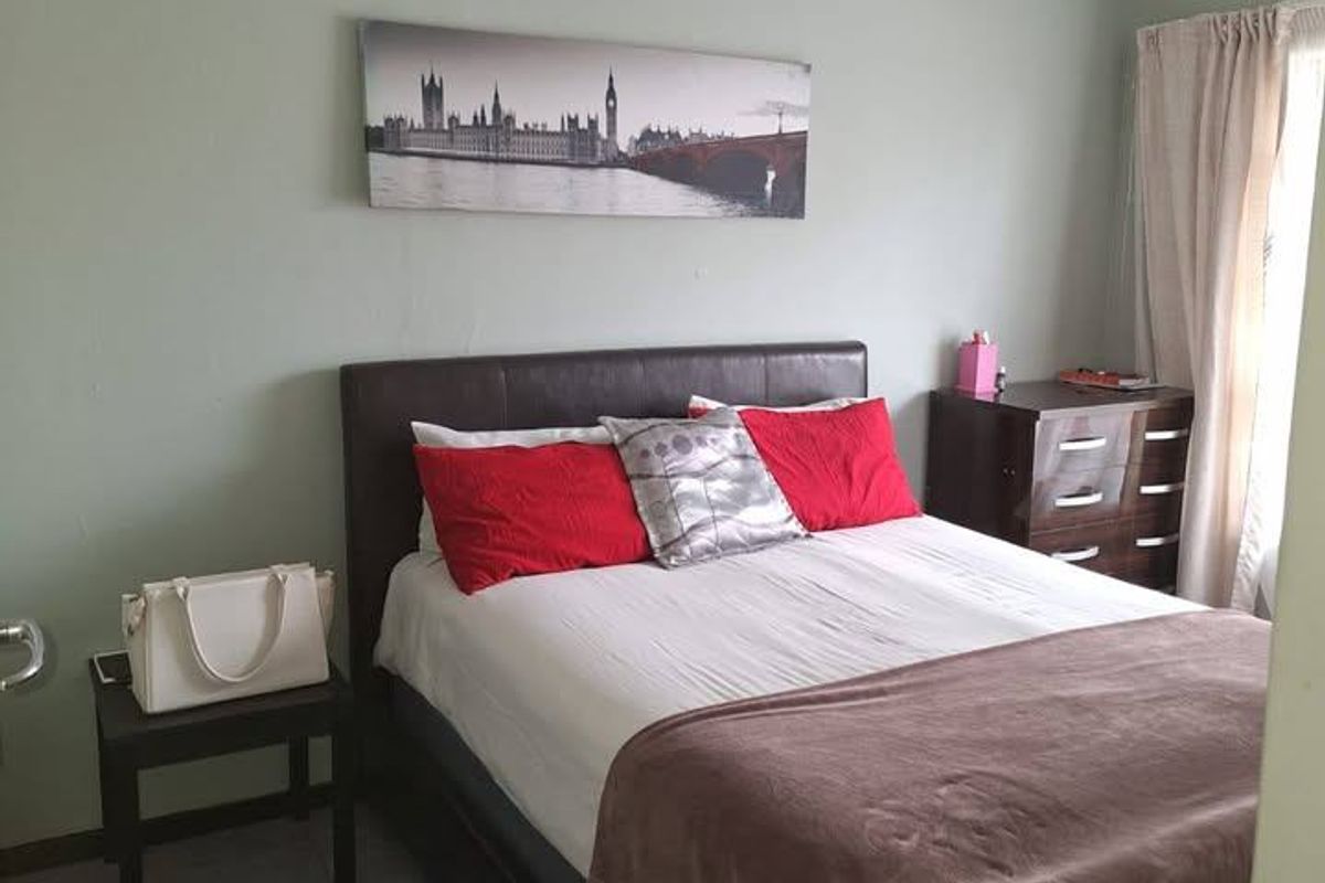 A standard bedroom featuring tiled flooring and a ceiling fan, providing a functional space for rest.