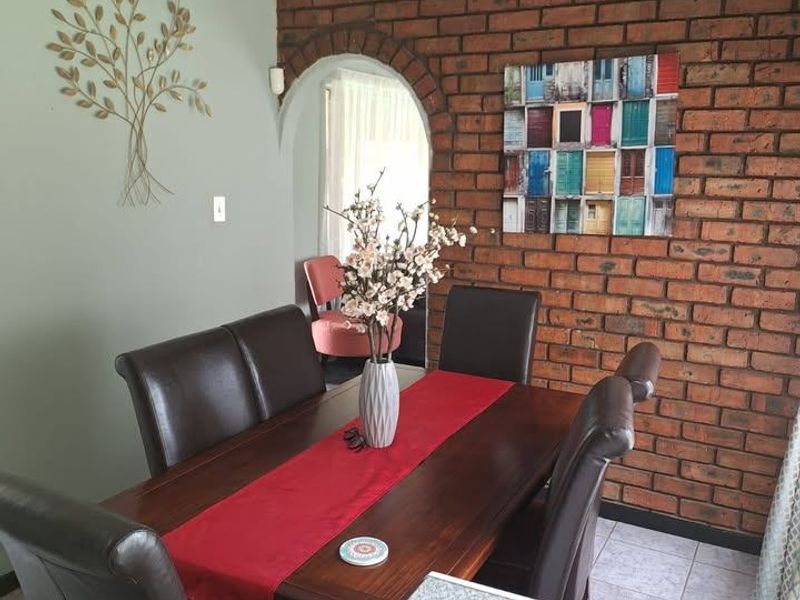 Dining room featuring an exposed brick feature wall, arched entryway, and tiled flooring, providing a warm and characterful space for meals.