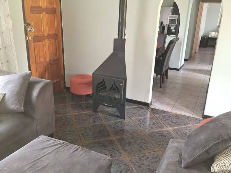 Living room featuring a freestanding fireplace, tiled flooring, and an arched doorway leading to the adjacent dining area.