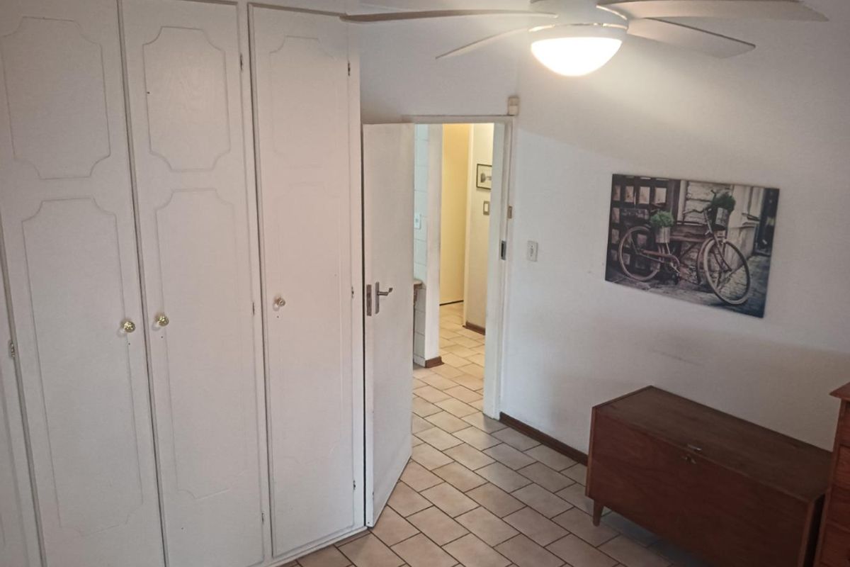 Bedroom featuring built-in cupboards, a ceiling fan, and tiled flooring, with direct access to the hallway.