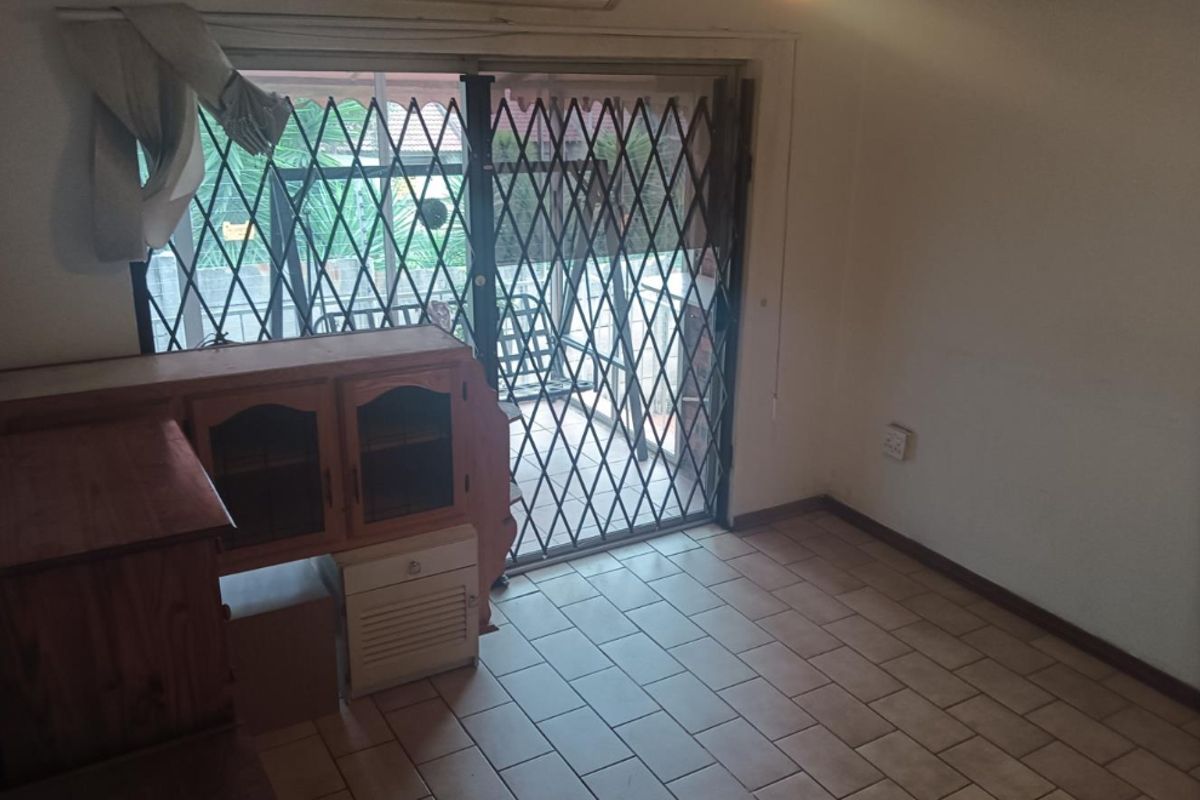 Living area featuring tiled flooring, a ceiling fan, split-system air conditioning, and a sliding door with a security gate leading to the patio.