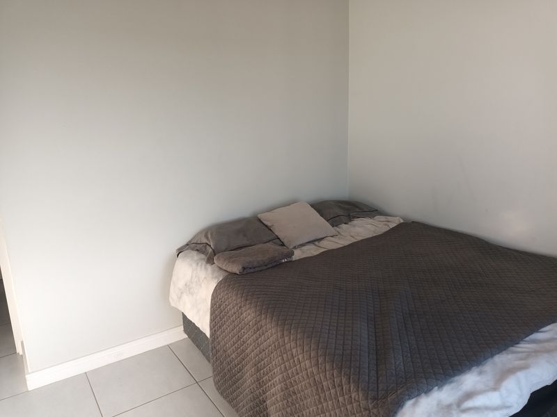 A simple bedroom featuring neutral wall finishes and tiled flooring, providing a clean and functional space.