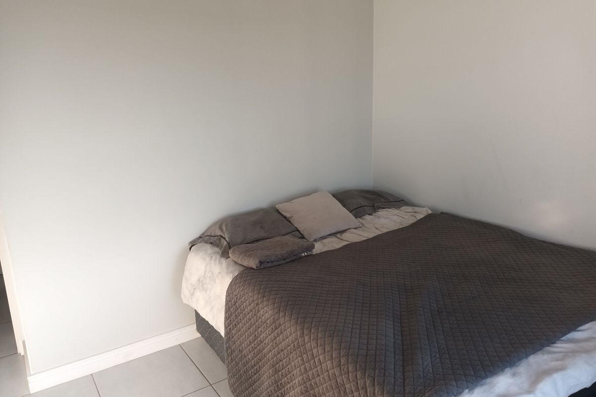 A simple bedroom featuring neutral wall finishes and tiled flooring, providing a clean and functional space.