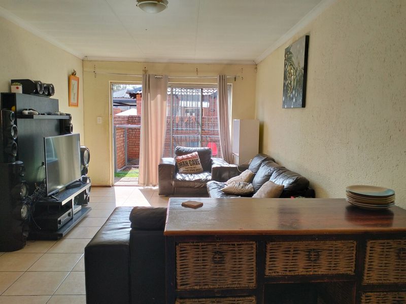 A living room featuring tiled flooring and a sliding glass door providing access to the exterior patio area.