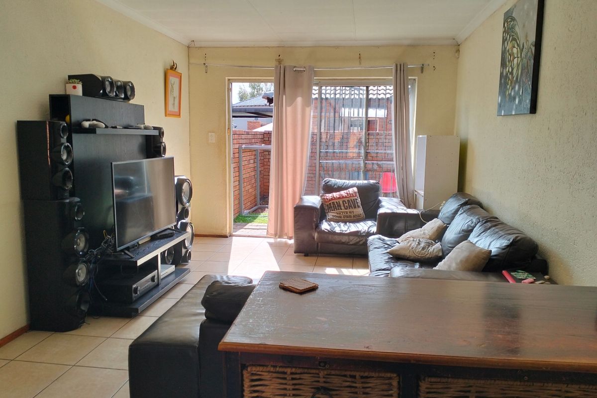 A living room featuring tiled flooring and a sliding glass door providing access to the rear patio area.