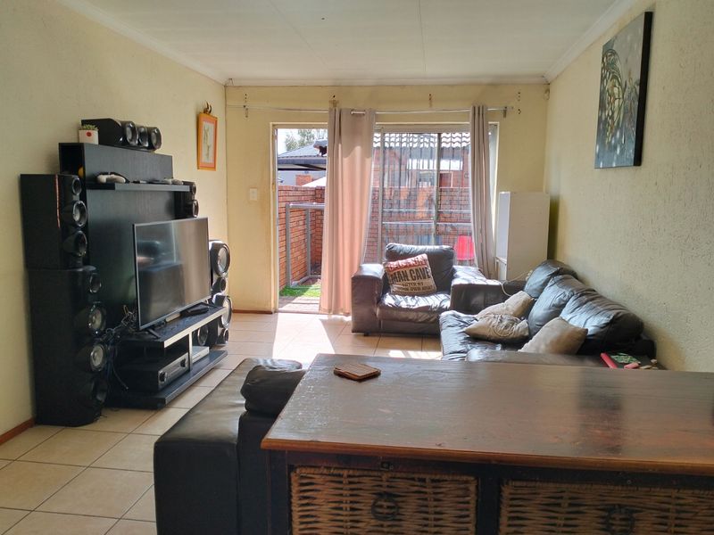 A living room featuring tiled flooring and a sliding glass door providing access to the rear patio area.