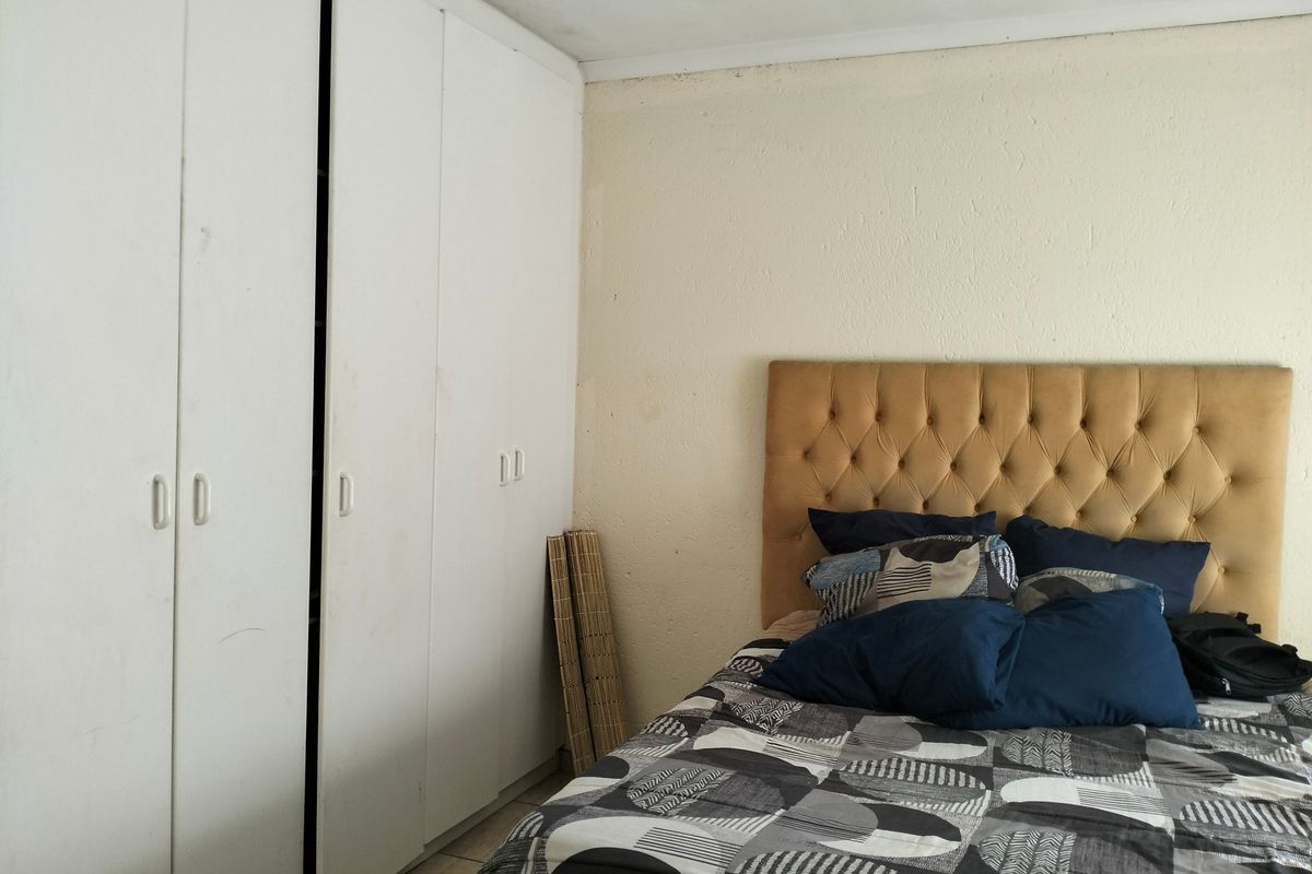 A bedroom featuring built-in cupboards with visible wear and a textured wall finish, offering a functional space ready for cosmetic updates.