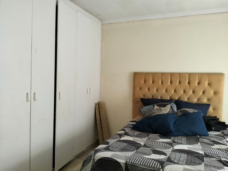 A bedroom featuring built-in cupboards with visible wear and a textured wall finish, offering a functional space ready for cosmetic updates.