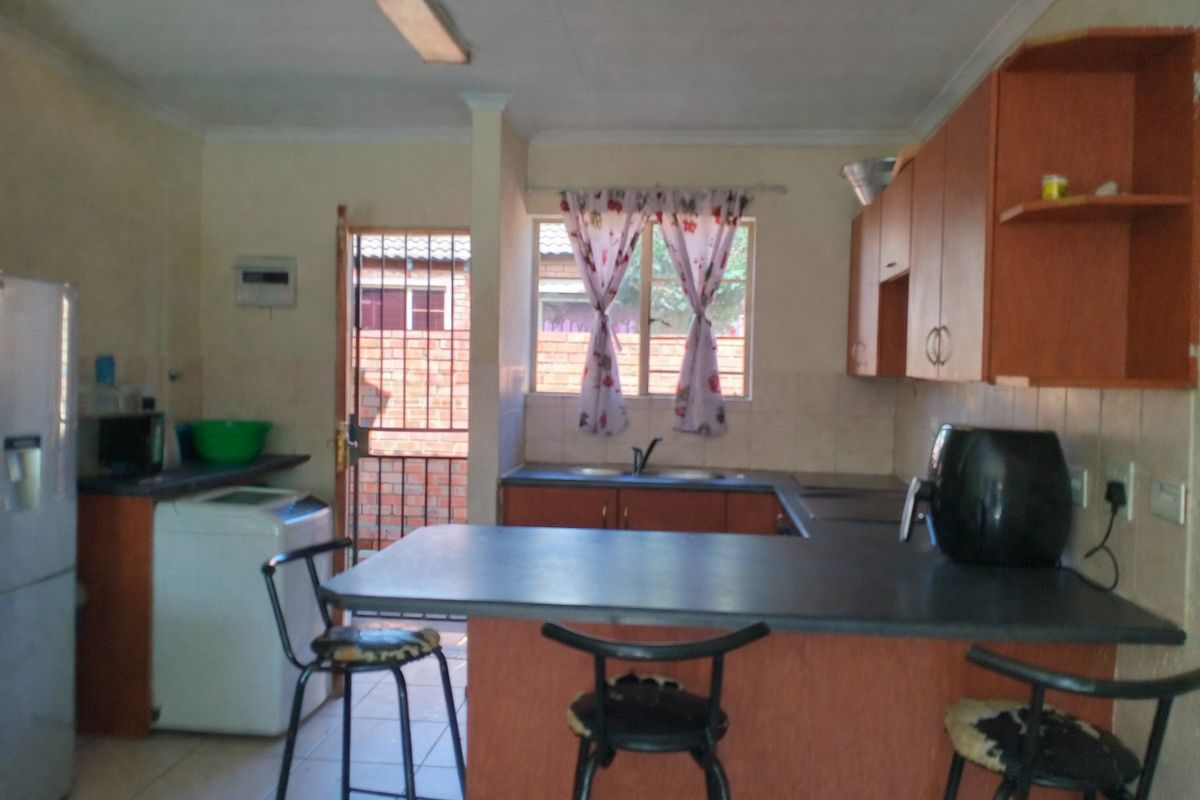 A functional kitchen featuring built-in cabinetry, laminate countertops, and a breakfast nook, with direct access to an exterior security gate.