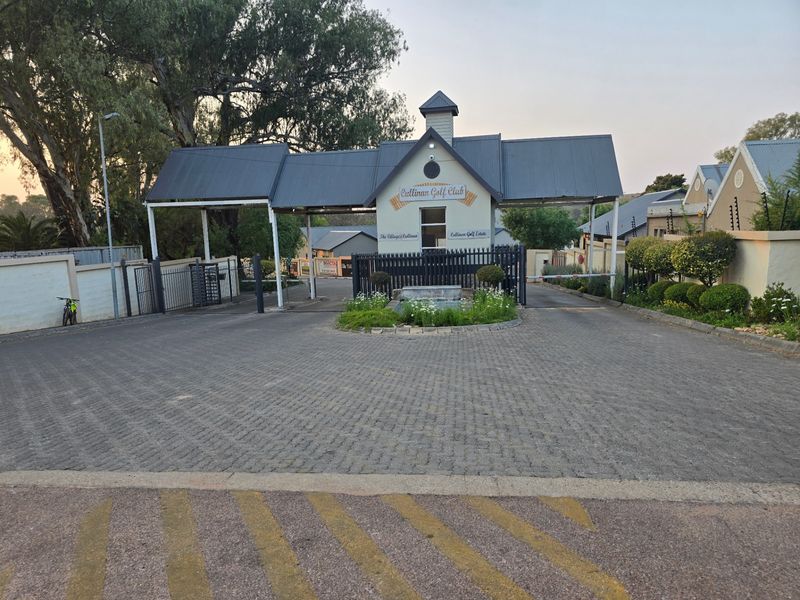 The entrance to the Cullinan Golf Estate featuring a paved driveway, security gatehouse, and well-maintained landscaped garden beds.