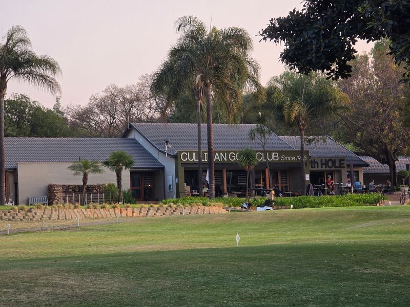 Exterior view of the Cullinan Golf Club building featuring a tiled roof, patio area, and well-maintained surrounding landscape.