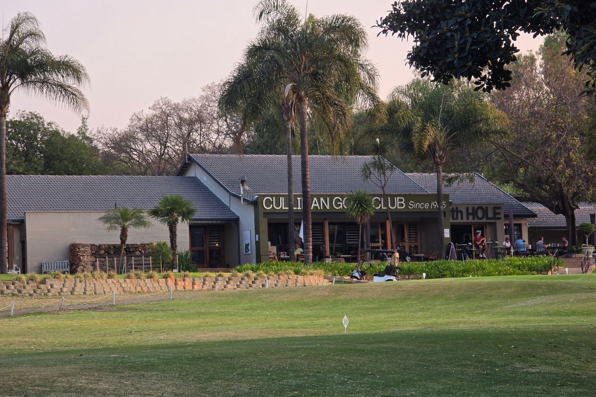 Exterior view of the Cullinan Golf Club building featuring a tiled roof, patio area, and well-maintained surrounding landscape.