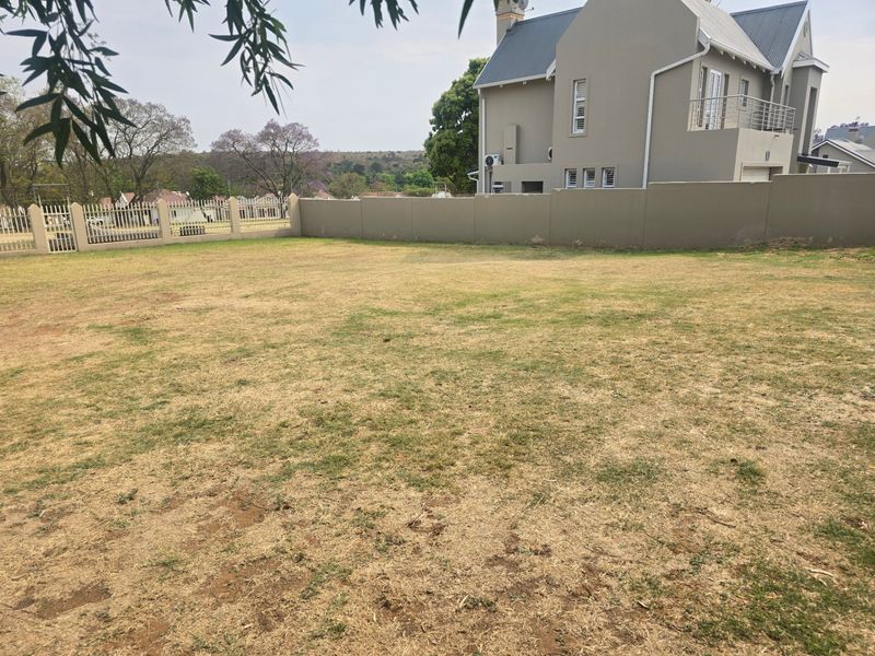 A spacious, level residential garden area featuring a perimeter wall and metal fencing, offering a clear view of the adjacent property.