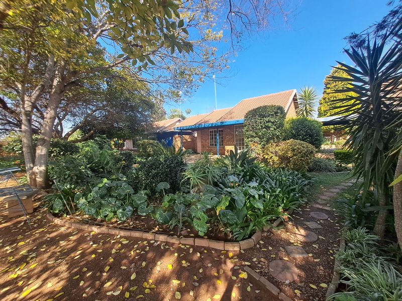 A view of the rear exterior of the townhouse featuring a well-established garden with mature trees and a stone pathway leading to the building.