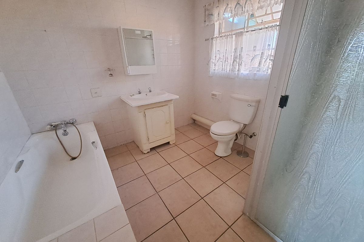 A dated bathroom featuring a bathtub, vanity cabinet, toilet, and separate shower enclosure with tiled finishes throughout.