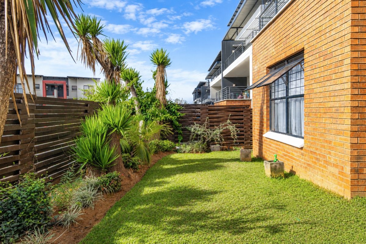 A well-maintained rear garden area featuring a brick exterior wall, timber privacy fencing, and established landscaping.