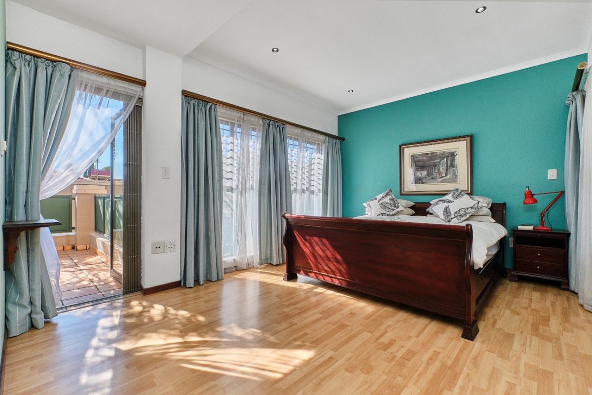 Spacious bedroom featuring laminate flooring, recessed lighting, and direct access to a private balcony through sliding glass doors.