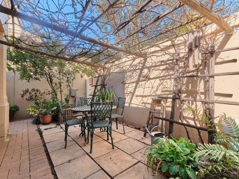 A private courtyard patio featuring paved flooring and a rustic wooden pergola, providing a cozy outdoor space for relaxation.