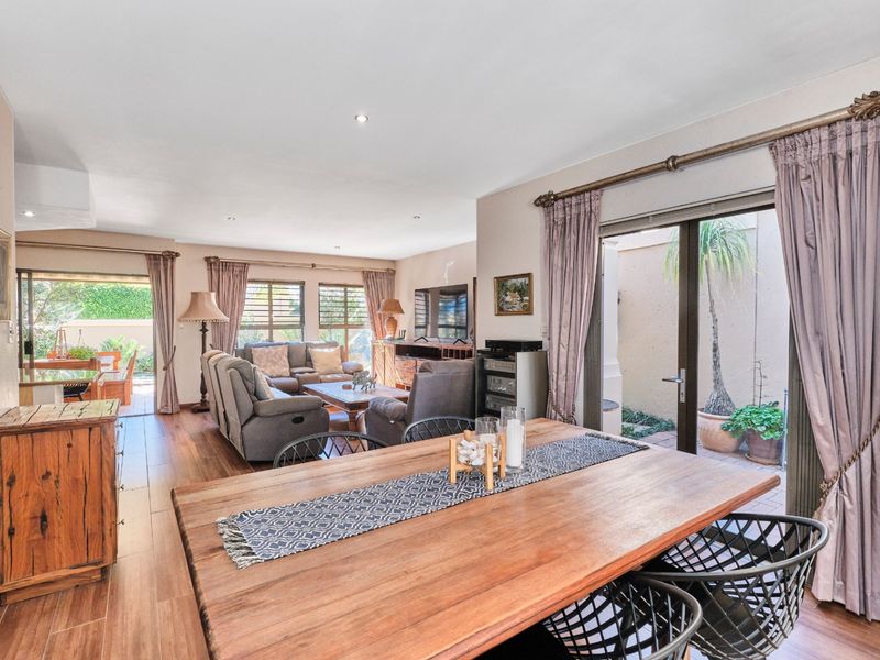 Spacious open-plan living and dining area featuring wood-look tile flooring, recessed lighting, and large sliding glass doors providing access to the outdoor patio.