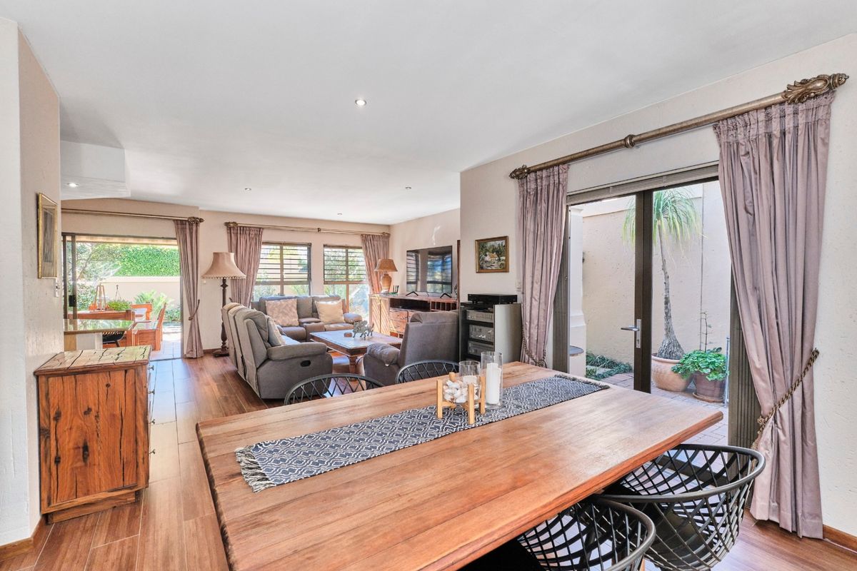 Spacious open-plan living and dining area featuring wood-look tile flooring, recessed lighting, and large sliding glass doors providing access to the outdoor patio.