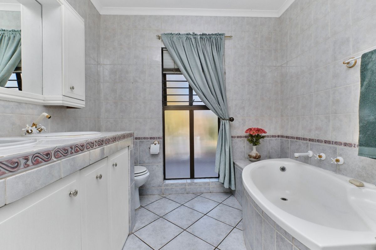 A functional bathroom featuring a built-in vanity, tiled walls and flooring, and a built-in bathtub with classic fixtures.