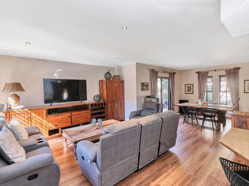 Spacious open-plan living and dining area featuring laminate flooring, recessed downlighting, and direct access to the outdoor space through sliding glass doors.