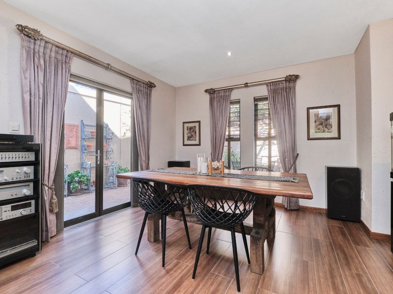 A well-maintained dining room featuring wood-look laminate flooring, recessed lighting, and large sliding glass doors providing access to an outdoor patio area.