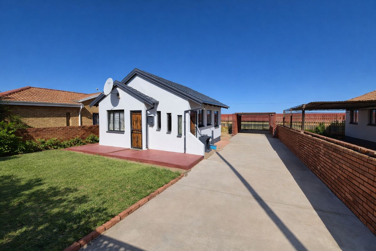 Front view of a detached house featuring a concrete driveway, brick boundary walls, and a well-maintained lawn area.