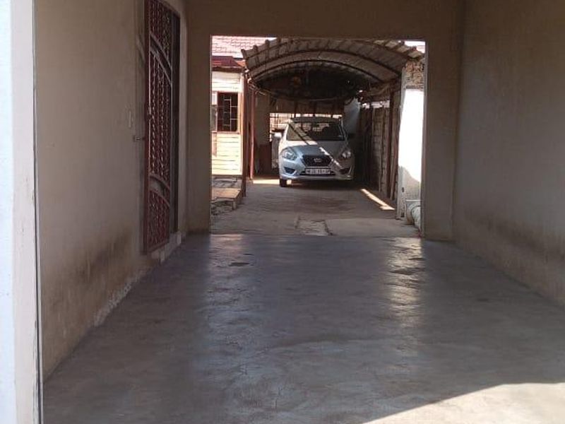 A covered garage space featuring concrete flooring and a metal security gate, providing secure off-street parking.