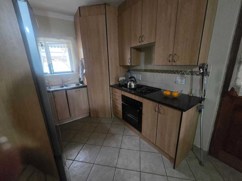 A functional kitchen featuring light wood-finish cabinetry, granite countertops, a built-in oven with gas hob, and tiled flooring.