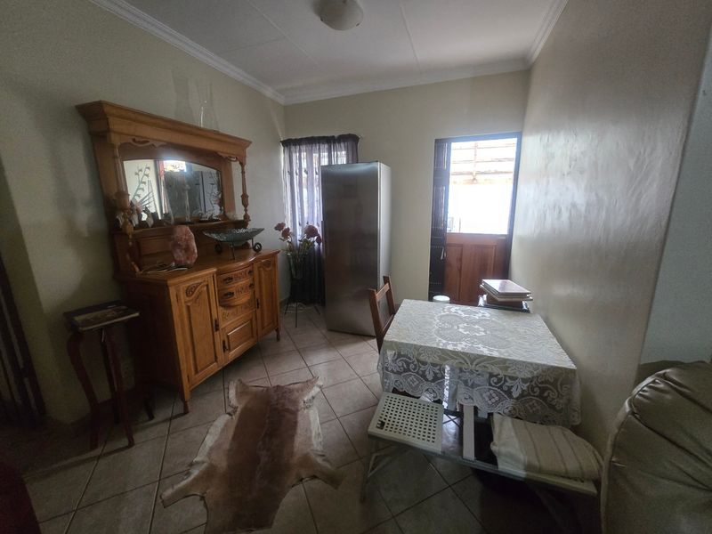 A functional dining area featuring tiled flooring, ceiling cornice detailing, and a stable-style door providing access to the exterior.