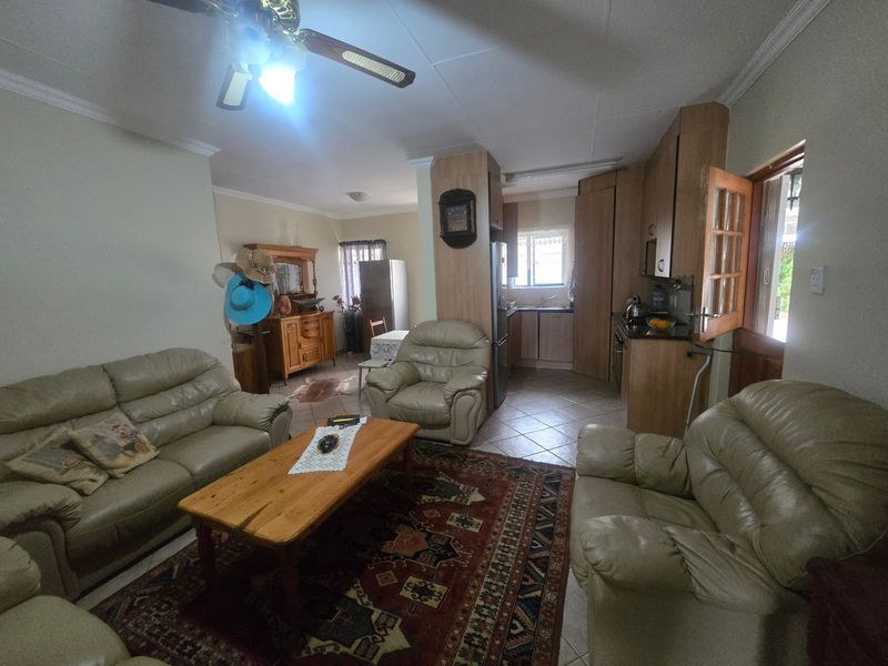 Open plan living and kitchen area featuring tiled flooring, ceiling fan, and functional built-in cabinetry, offering a practical layout for daily living.