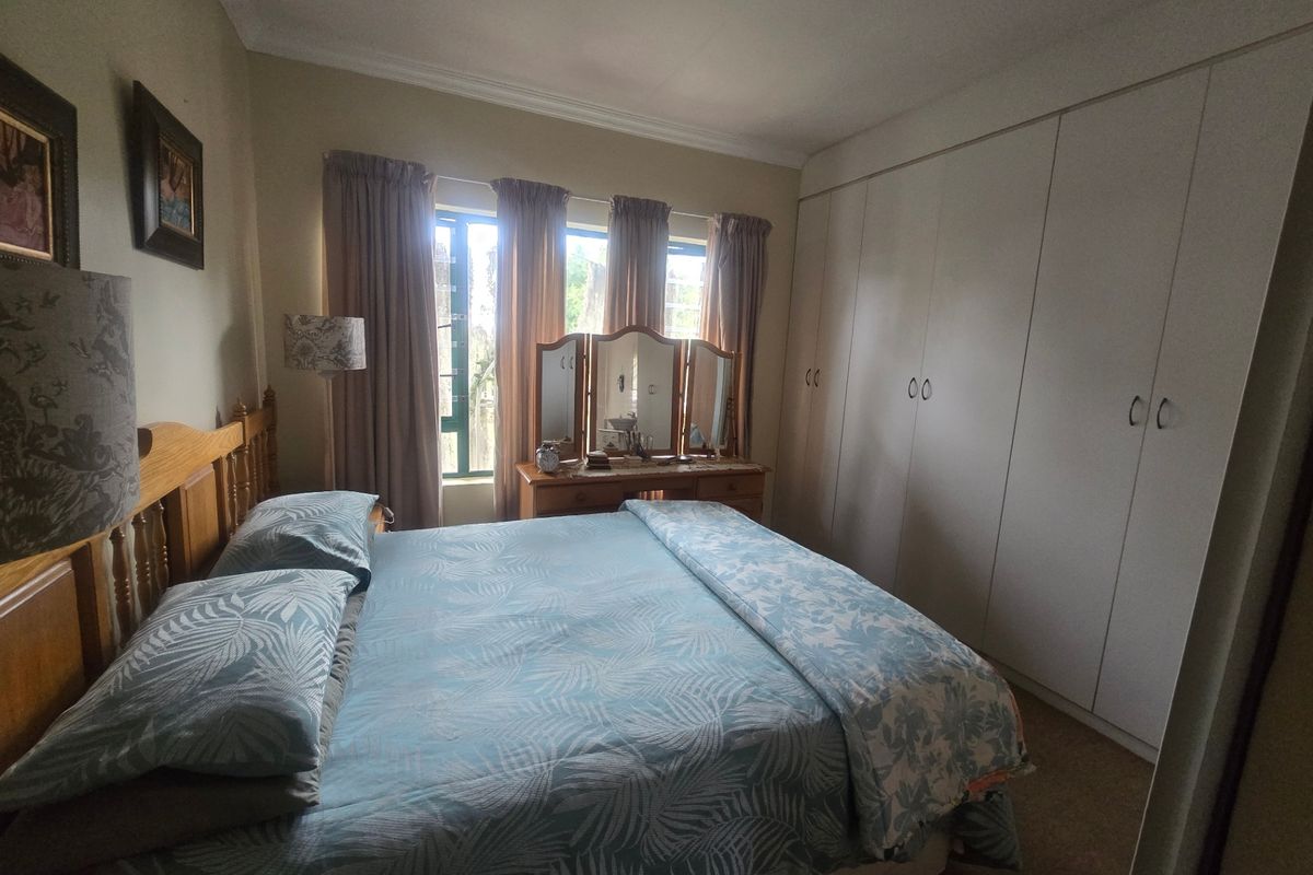 A well-proportioned bedroom featuring extensive built-in cupboards, neutral wall finishes, and large windows allowing for natural light.