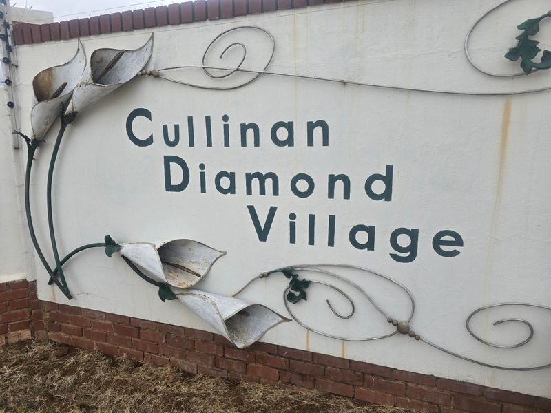 Entrance signage for Cullinan Diamond Village featuring a masonry boundary wall with decorative metalwork and integrated electric security fencing.