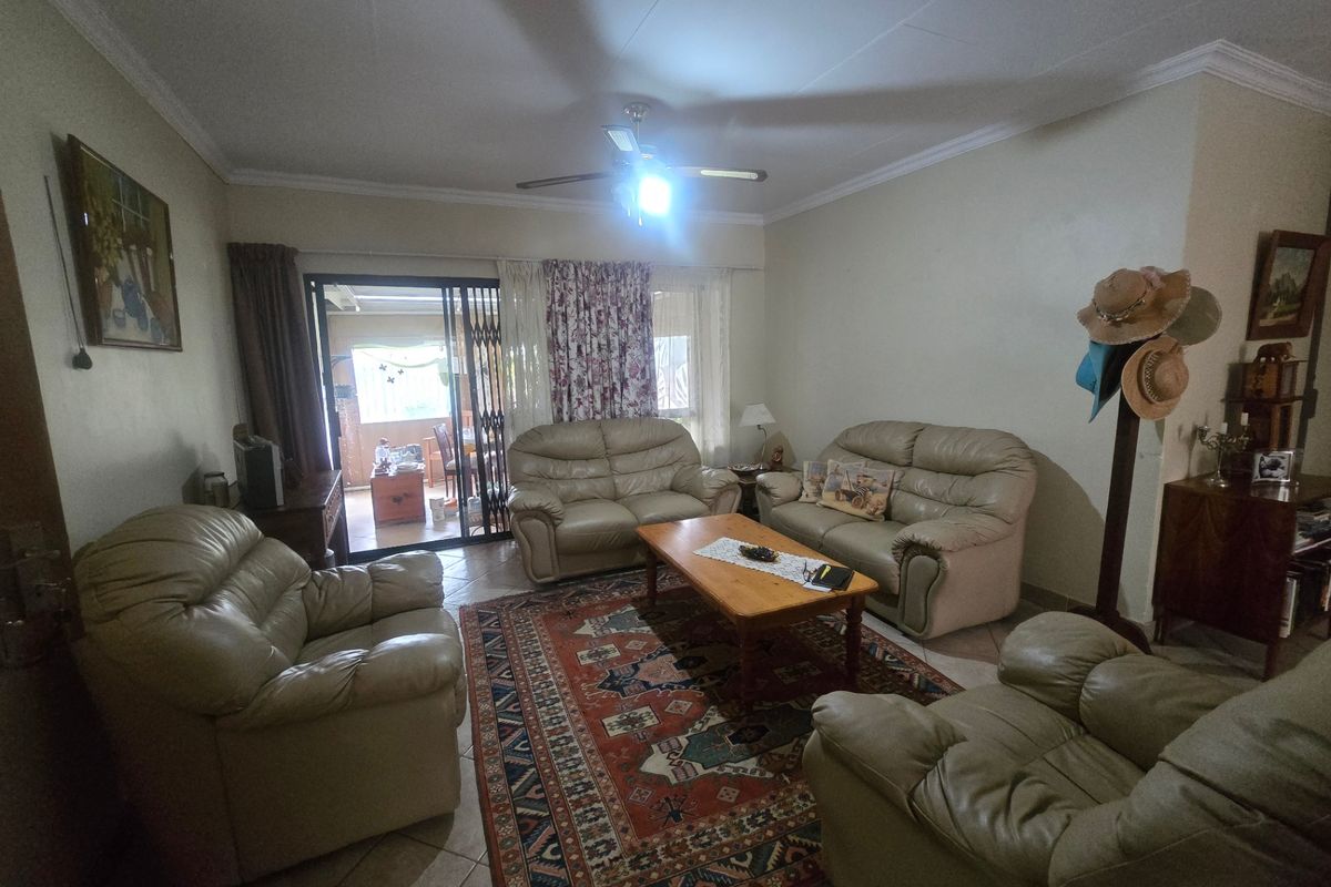 A spacious living room featuring tiled flooring, a ceiling fan, and a sliding glass door providing access to the patio area.