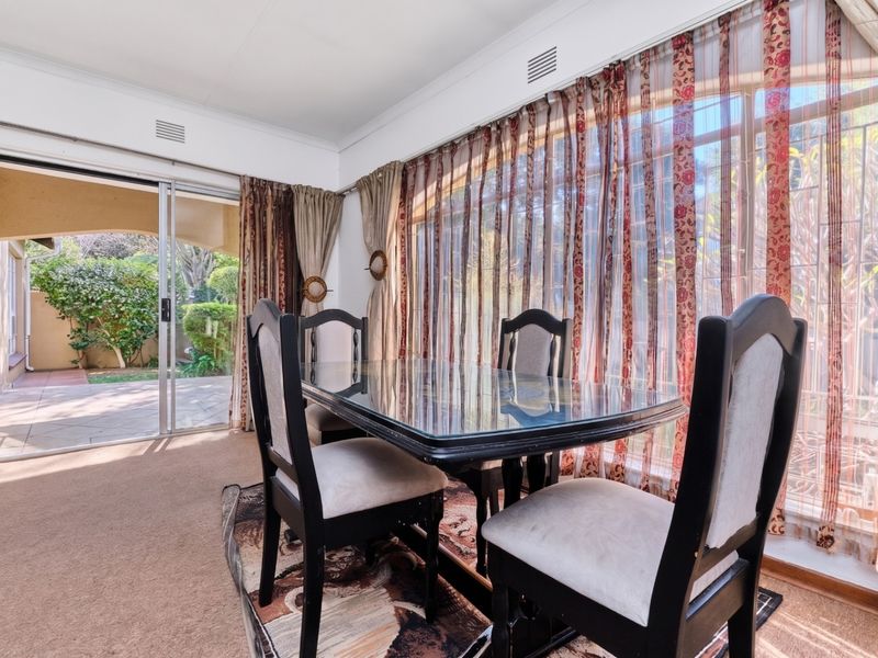 Dining room featuring large windows with security bars and a sliding glass door providing direct access to the outdoor patio area.