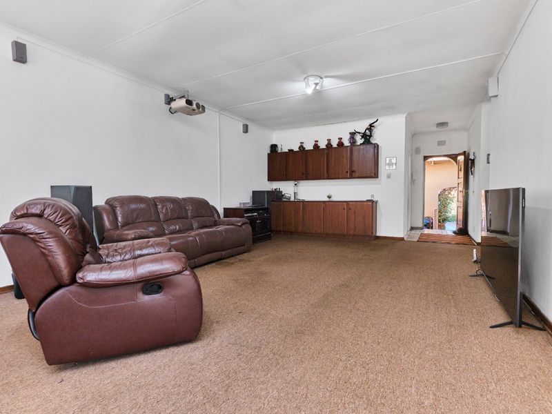 Spacious living room featuring built-in cabinetry, a ceiling-mounted projector, and carpeted flooring, offering a functional space with potential for modernization.